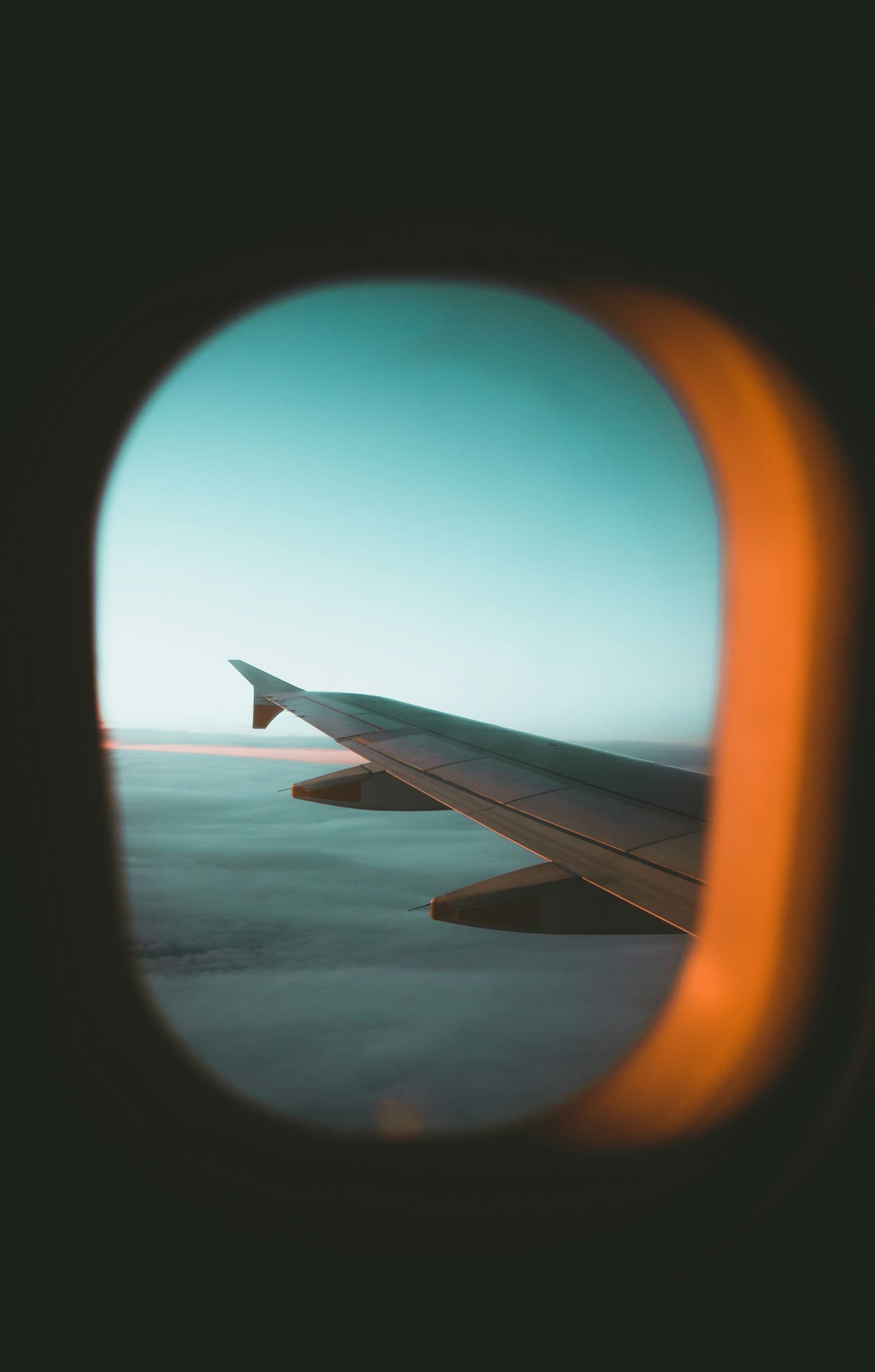 View of an airplane wing through the cabin window at sunset