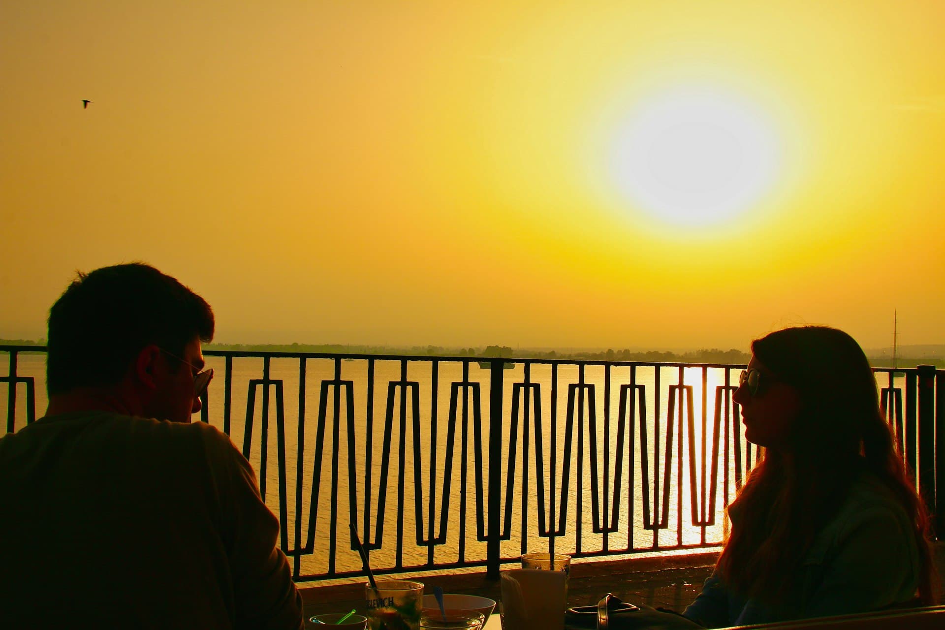 A couple watching the sunset over the water from a terrace