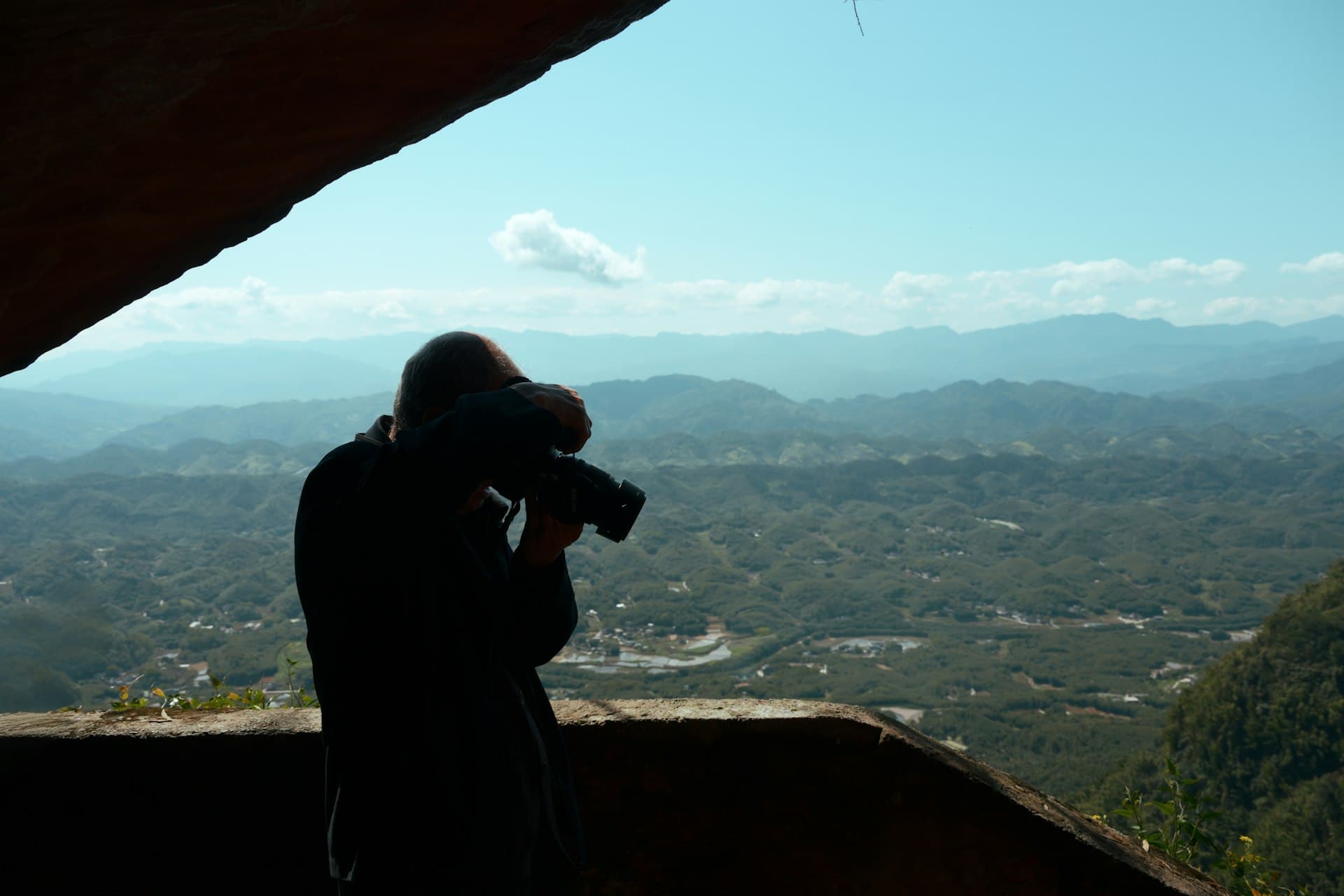 Silhouette of a photographer capturing a vast mountainous landscape