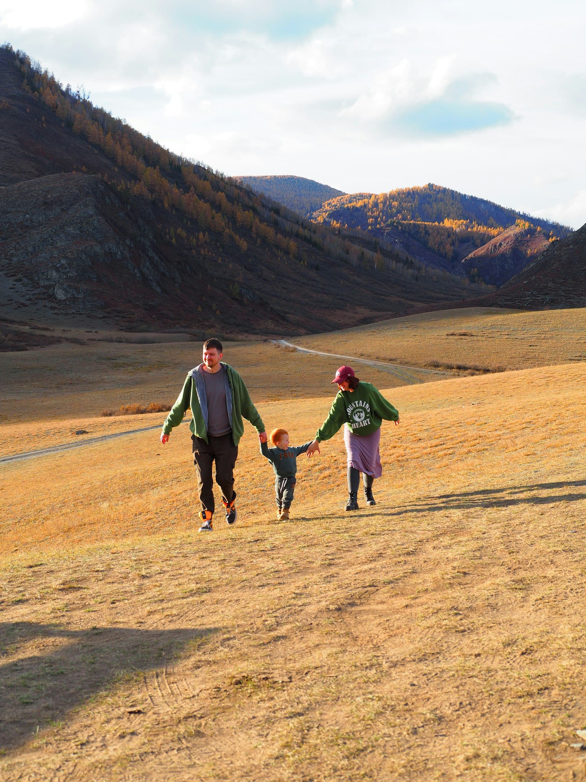 A family walking hand in hand across a grassy hillside
